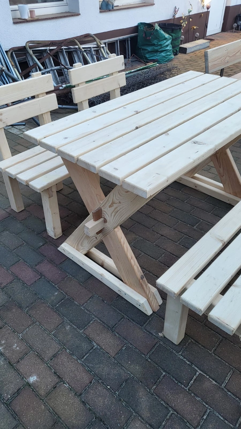 Dach,Wand und Holzkonstruktion - Handgefertigte Holzkunst - Ein klassisches Gartenmöbelset aus Holz, bestehend aus einem rechteckigen Picknicktisch und zwei passenden, freistehenden Bänken. Das Set ist aus hellem, druckimprägniertem Holz gefertigt und hat ein stabiles A-förmiges Gestell.