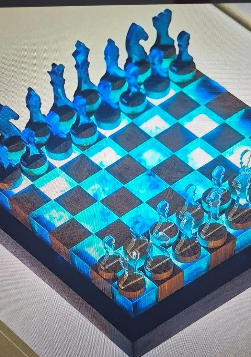 Dach,Wand und Holzkonstruktion - Handgefertigte Holzkunst - Ein modernes, handgefertigtes Schachbrett mit abwechselnden Feldern aus Holz und leuchtendem, blauem Epoxidharz. Transparente, blaue und klare Schachfiguren aus Harz sind auf dem leuchtenden Brett angeordnet.